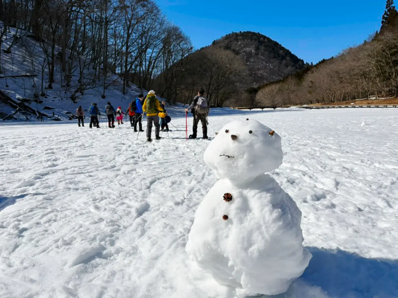 雪だるまと立ち去るツアーメンバーの背中